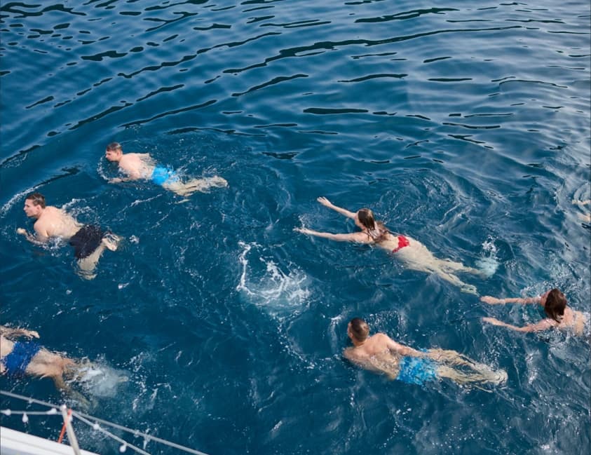 Friends swimming in the blue sea beside a boat